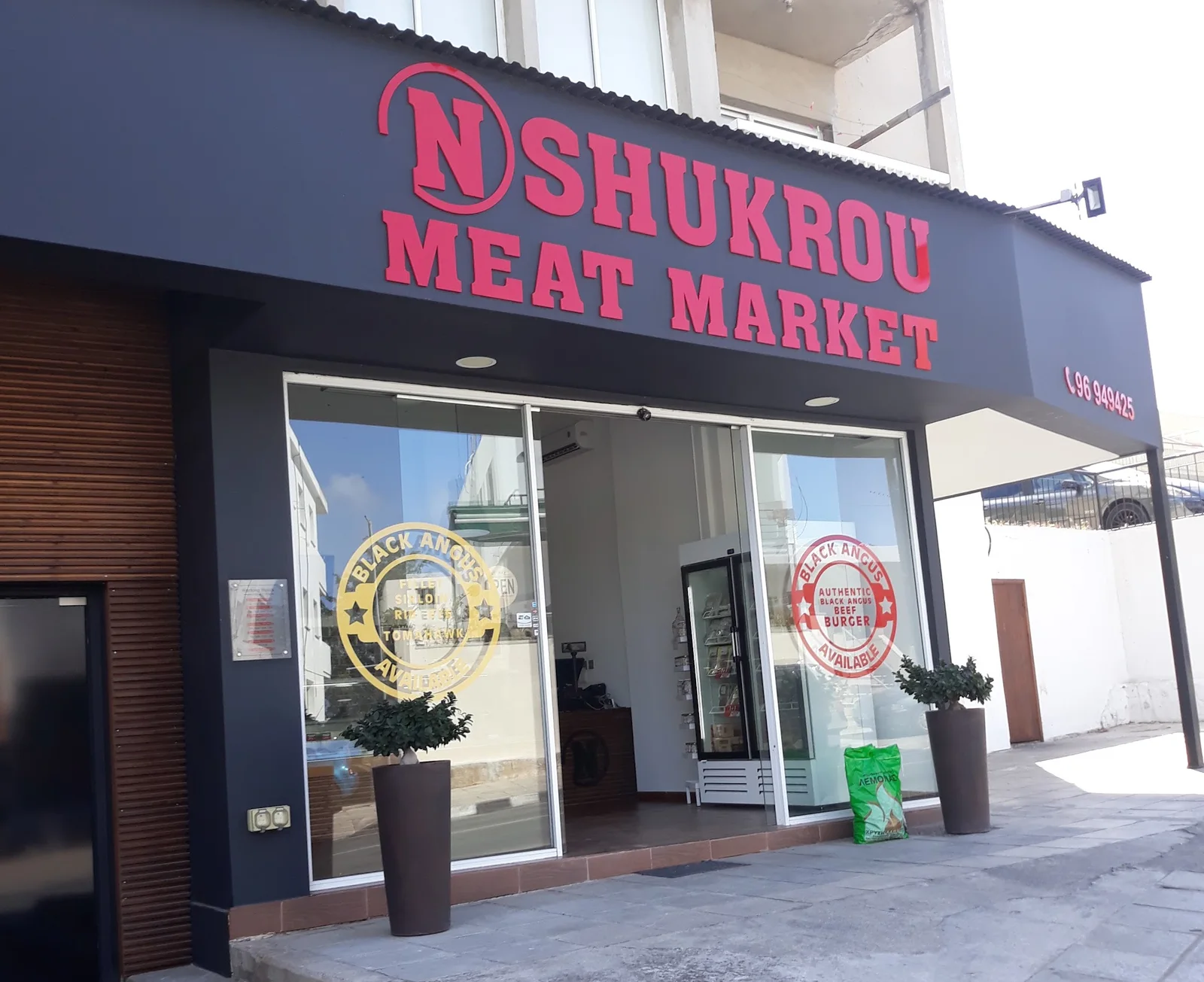 The N. Shukrou Meat Market shop front with red letters and Black Angus signs on the glass